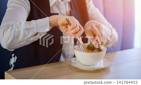 Mature Businesswoman Stirring Soup In Cafe, Steaming Broth And Spoon Motion, Warm Natural Light On Blazer Sleeves, Mindful Slow Pace, Comforting Aroma, Quiet Midday Pause From Work, Attentive Hands 141784452