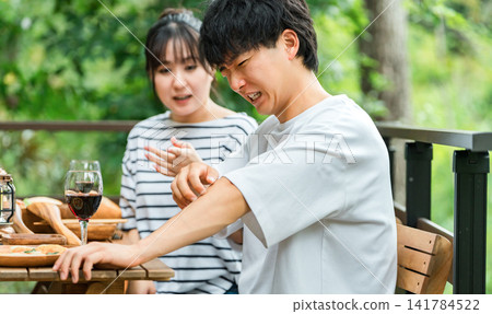 A couple is having trouble with insect bites while eating outdoors. A couple is having trouble with insect bites while eating outdoors. 141784522