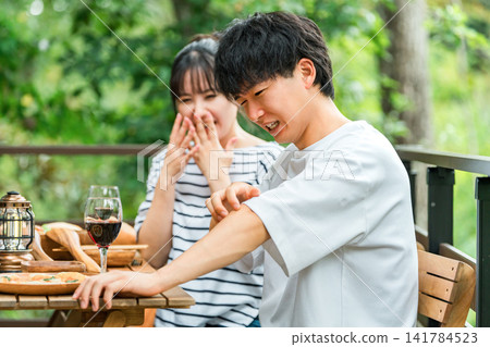 A couple is having trouble with insect bites while eating outdoors. A couple is having trouble with insect bites while eating outdoors. 141784523