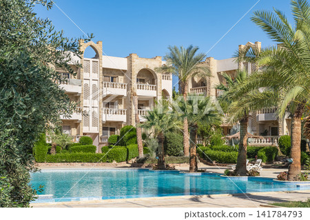 Luxury tropical resort swimming pool and garden landscaping. Modern architecture with tropical palms Luxury tropical resort swimming pool and garden landscaping. Modern architecture with tropical palms 141784793