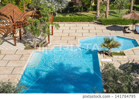 Luxury tropical resort swimming pool and garden landscaping. Modern architecture with tropical palms Luxury tropical resort swimming pool and garden landscaping. Modern architecture with tropical palms 141784795