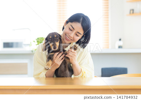 Teleworking, online meeting: A woman holding a dog appears on the computer screen. Teleworking, online meeting: A woman holding a dog appears on the computer screen. 141784932