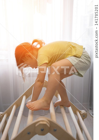 Child actively playing climbing wooden pikler triangle Child actively playing climbing wooden pikler triangle 141785201