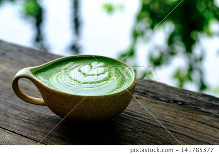 Serene Morning Cup of Matcha Latte with Leaf Art on Wooden Table Serene Morning Cup of Matcha Latte with Leaf Art on Wooden Table 141785377