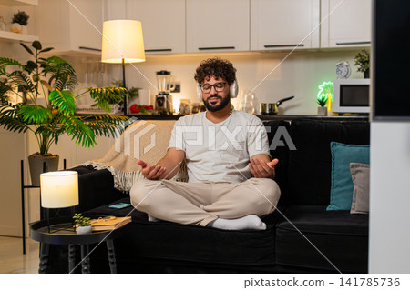 Arabian man in headphones meditates with rain sound deep breathing calm relax chill peaceful evening Arabian man in headphones meditates with rain sound deep breathing calm relax chill peaceful evening 141785736