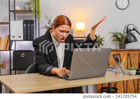 Young businesswoman frustrated laptop freezes hits table grabs head presses ctrl alt del for restart Young businesswoman frustrated laptop freezes hits table grabs head presses ctrl alt del for restart 141785754
