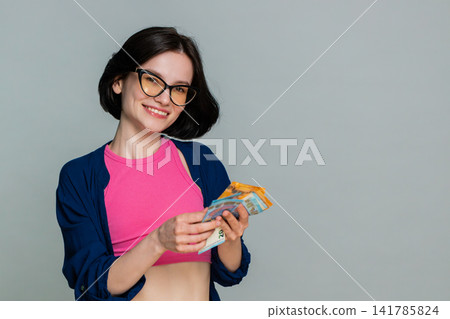 Young woman smiling counting cash euro money expressing financial success profit earnings wealth 141785824
