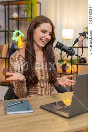 Young woman hosts vlog speaks on studio mic welcomes audience shares key info and asks to subscribe Young woman hosts vlog speaks on studio mic welcomes audience shares key info and asks to subscribe 141785854