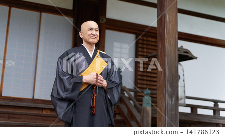 Portrait of a monk holding prayer beads in front of the main hall. 141786123