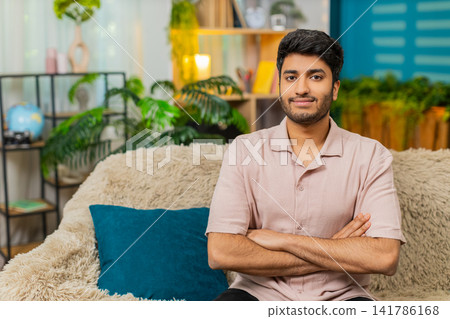 Indian man on home sofa changing serious face into smile for strong portrait video at home indoors Indian man on home sofa changing serious face into smile for strong portrait video at home indoors 141786168