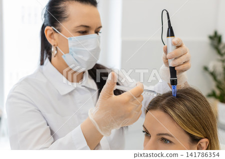 Trichologist doing woman hair regeneration procedure, dermapen microneedling, vitamin injections Trichologist doing woman hair regeneration procedure, dermapen microneedling, vitamin injections 141786354