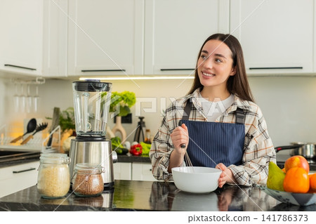 Young woman whisking batter in kitchen preparing simple breakfast recipe for healthy eating habits Young woman whisking batter in kitchen preparing simple breakfast recipe for healthy eating habits 141786373