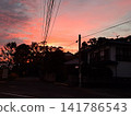 The twilight sky and residential area are painted in a vibrant crimson color. The twilight sky and residential area are painted in a vibrant crimson color. 141786543