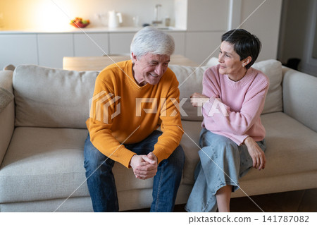 Relaxed elderly couple husband and wife sitting on couch at home joking and having fun together. Relaxed elderly couple husband and wife sitting on couch at home joking and having fun together. 141787082