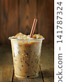 Iced coffee cold brew in a clear plastic cup standing on an aged wooden table 141787324