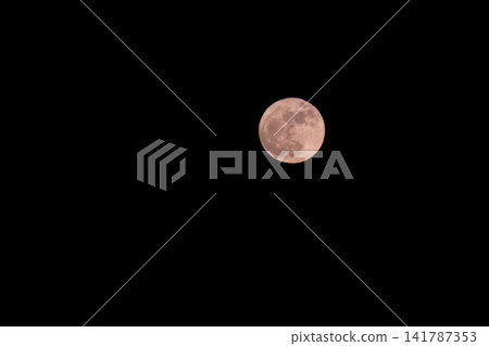 A pink full moon floating in the dark night sky A pink full moon floating in the dark night sky 141787353
