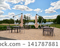 Lakeside outdoor terrace with tables and umbrellas overlooking a scenic lake. 141787881