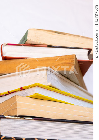 A stack of books arranged in a pile. The books vary in size and color, with visible spines and covers. Some have bookmarks protruding from them. A stack of books arranged in a pile. The books vary in size and color, with visible spines and covers. Some have bookmarks protruding from them. 141787978