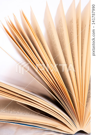 An opened book with pages fanned out, displaying a textured paper surface. The background is soft and neutral, emphasizing the book's details. An opened book with pages fanned out, displaying a textured paper surface. The background is soft and neutral, emphasizing the book's details. 141787990