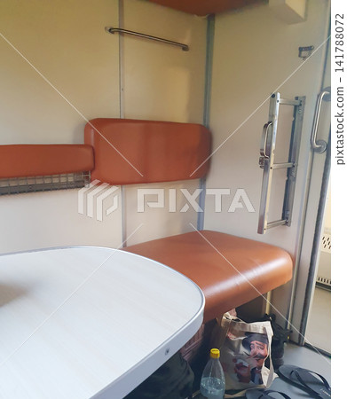 Empty passenger train compartment interior with brown leather seats, wooden table, and luggage underneath Empty passenger train compartment interior with brown leather seats, wooden table, and luggage underneath 141788072