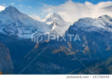 Swiss Alps Switzerland snow mountain peaks of Breithorn range rising above deep valley under blue sky with clouds Swiss Alps Switzerland snow mountain peaks of Breithorn range rising above deep valley under blue sky with clouds 141788348
