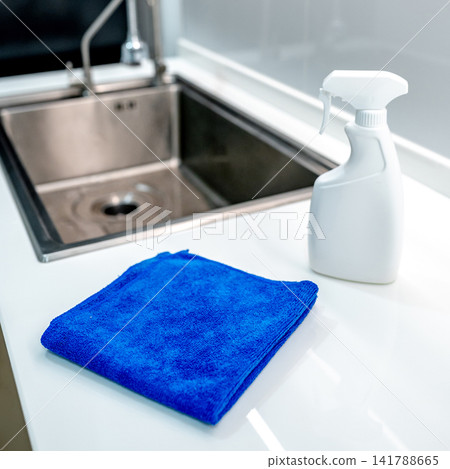 Blue microfiber cloth and detergent spray bottle on modern white countertop Blue microfiber cloth and detergent spray bottle on modern white countertop 141788665