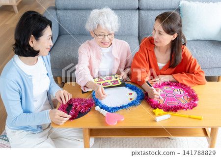A senior female friend who engages in her fan activities in the living room. A senior female friend who engages in her fan activities in the living room. 141788829
