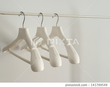White Coat Hangers on White Metal Rack, Chrome Hook Close-Up White Coat Hangers on White Metal Rack, Chrome Hook Close-Up 141789549