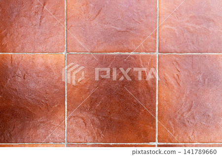 Top view of red ceramic floor tiles with grout lines forming geometric pattern. Textured tile surface suitable as background for flooring, interior design, renovation, construction, seamless texture Top view of red ceramic floor tiles with grout lines forming geometric pattern. Textured tile surface suitable as background for flooring, interior design, renovation, construction, seamless texture 141789660