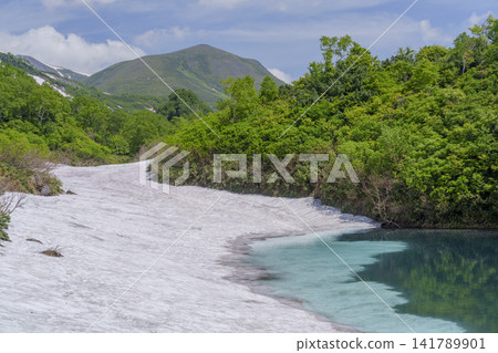 Hokkaido's Daisetsuzan: A breathtaking early summer scene of Shikibu Pond in the Daisetsuzan Plateau marshland and lingering snow. Hokkaido's Daisetsuzan: A breathtaking early summer scene of Shikibu Pond in the Daisetsuzan Plateau marshland and lingering snow. 141789901