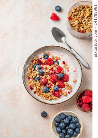Natural greek yogurt with granola, blueberry and raspberry in a bowl on a light textured background Natural greek yogurt with granola, blueberry and raspberry in a bowl on a light textured background 141789961