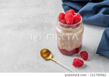 Oatmeal in a jar with raspberries overnight in alternative milk on a light background 141789962