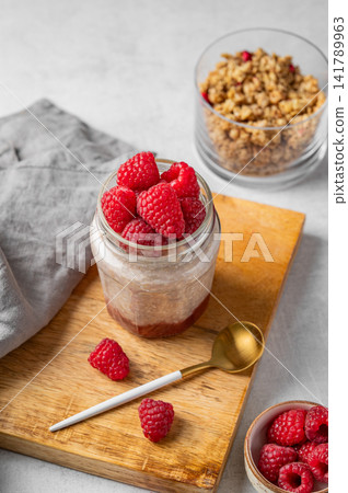 Oatmeal in a jar with raspberries overnight in alternative milk on a light background Oatmeal in a jar with raspberries overnight in alternative milk on a light background 141789963