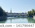 A view of Zurich across the Limmat River, showing the green spire of Prediger Church and the Grossmünster twin towers. 141790447