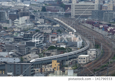 東海道線上的希望號新幹線在京都站附近沿著一條彎道行駛。 東海道線上的希望號新幹線在京都站附近沿著一條彎道行駛。 141790553