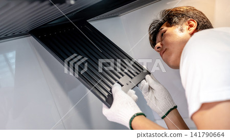 Asian male technician removing range hood filter looking inside the cooker hood Asian male technician removing range hood filter looking inside the cooker hood 141790664