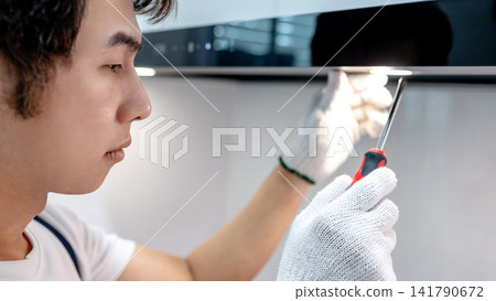 Asian male maintenance worker using screwdriver fixing light on cooker hood Asian male maintenance worker using screwdriver fixing light on cooker hood 141790672