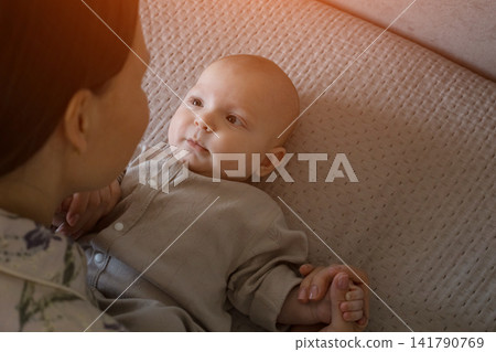Young mother bonding with infant baby on bed Young mother bonding with infant baby on bed 141790769