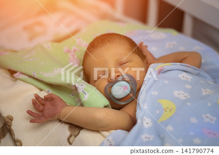 Newborn baby peacefully sleeping with pacifier in crib 141790774