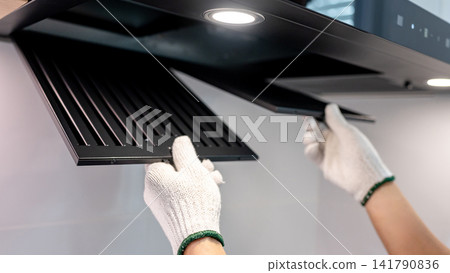 Male hand technician with protective gloves removing black range hood filter from cooker hood Male hand technician with protective gloves removing black range hood filter from cooker hood 141790836