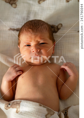 Newborn baby frowning with curious expression on blanket 141790844