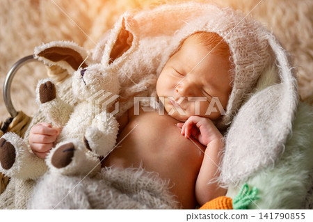 Newborn baby sleeping in bunny outfit holding plush rabbit Newborn baby sleeping in bunny outfit holding plush rabbit 141790855