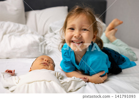 Young girl smiling next to sleeping newborn baby 141791093