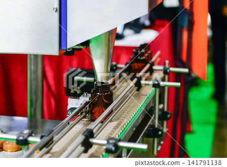 Automatic pill bottle filling machine on conveyor belt in pharmaceutical factory packaging line 141791138