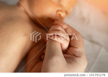 Newborn baby tiny hand grasping parent finger in tender moment Newborn baby tiny hand grasping parent finger in tender moment 141791276