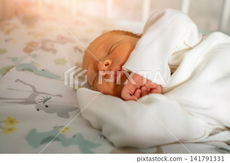 Newborn baby sleeping peacefully in crib with warm light Newborn baby sleeping peacefully in crib with warm light 141791331