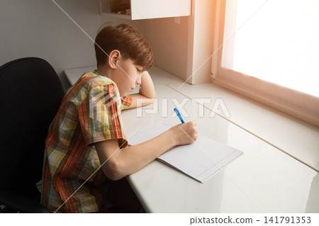 Young boy learning studying and writing homework at home Young boy learning studying and writing homework at home 141791353