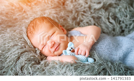 Newborn baby sleeping peacefully holding knitted toy Newborn baby sleeping peacefully holding knitted toy 141791383