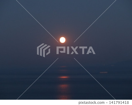 A quiet night scene with the light of the full moon reflected on the water's surface. A quiet night scene with the light of the full moon reflected on the water's surface. 141791418