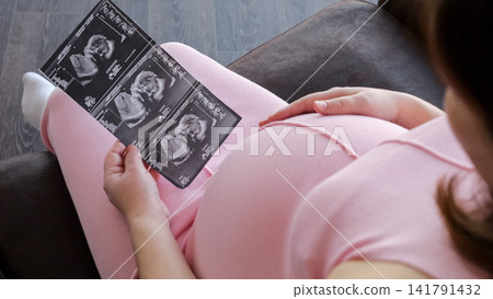 Pregnant woman holding baby ultrasound scan prints Pregnant woman holding baby ultrasound scan prints 141791432